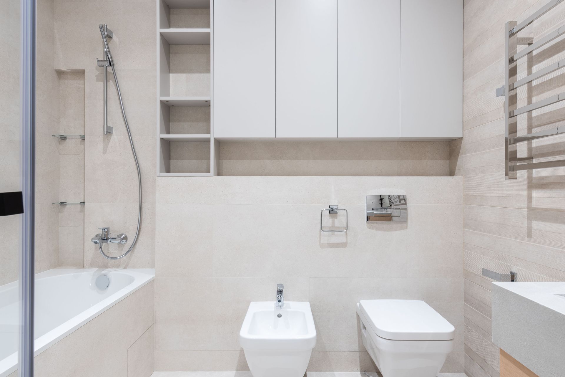 Interior of modern light bathroom with bidet and toilet next to sink and bath